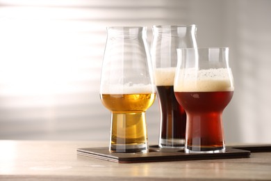 Photo of Glasses with different types of beer on wooden table indoors, closeup. Space for text