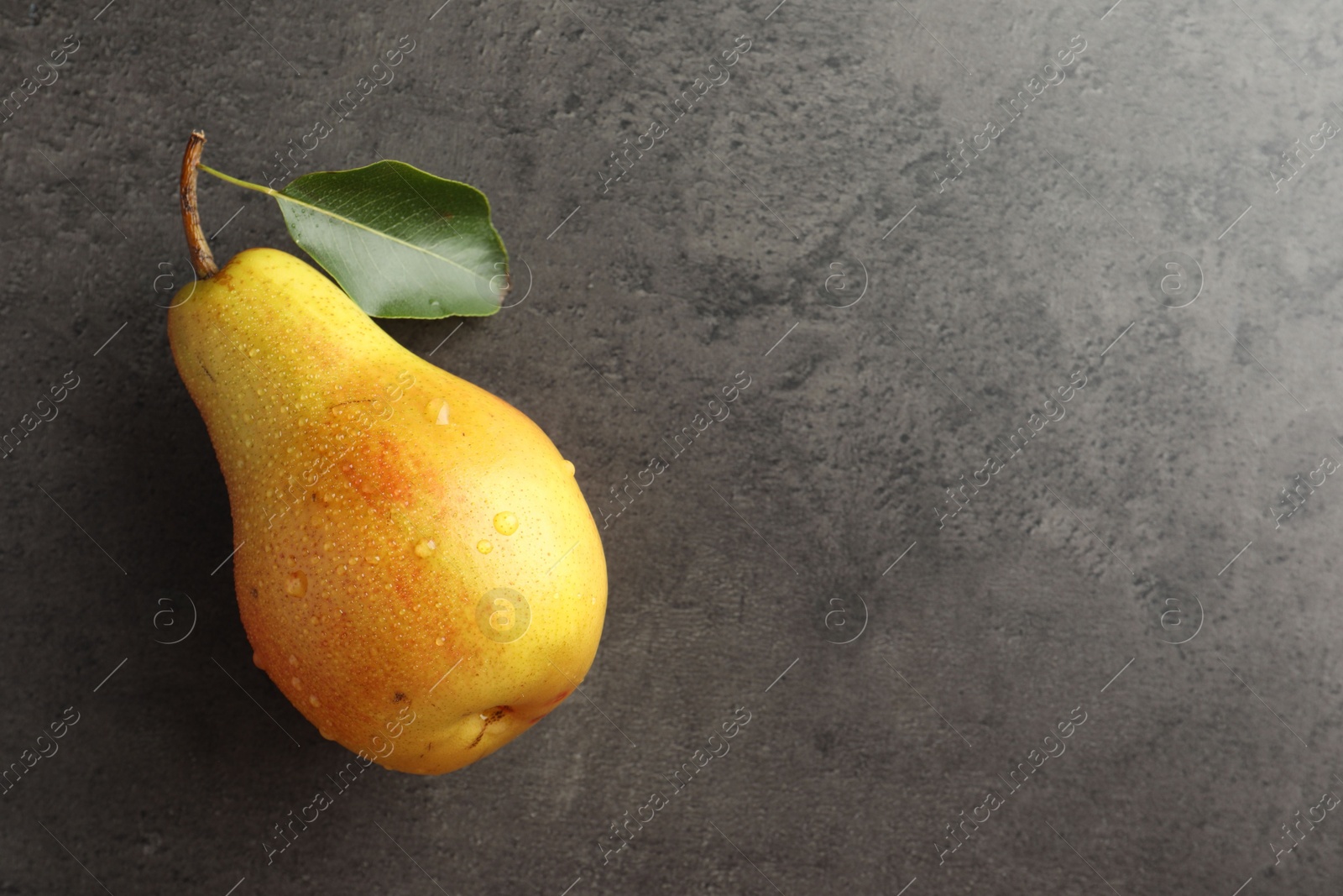 Photo of One ripe juicy pear on grey table, top view. Space for text