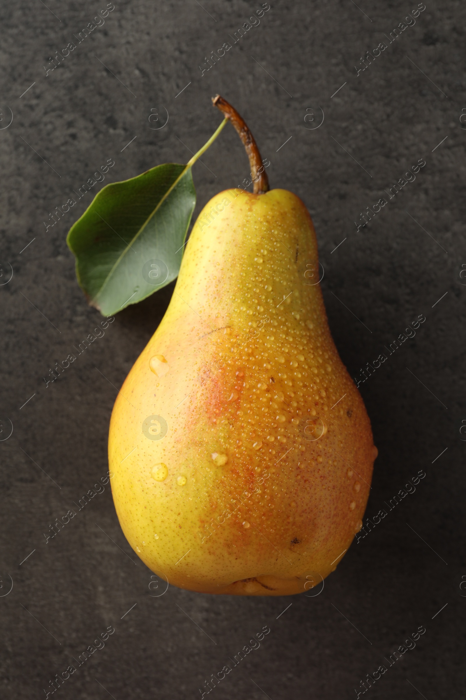 Photo of One ripe juicy pear on grey table, top view