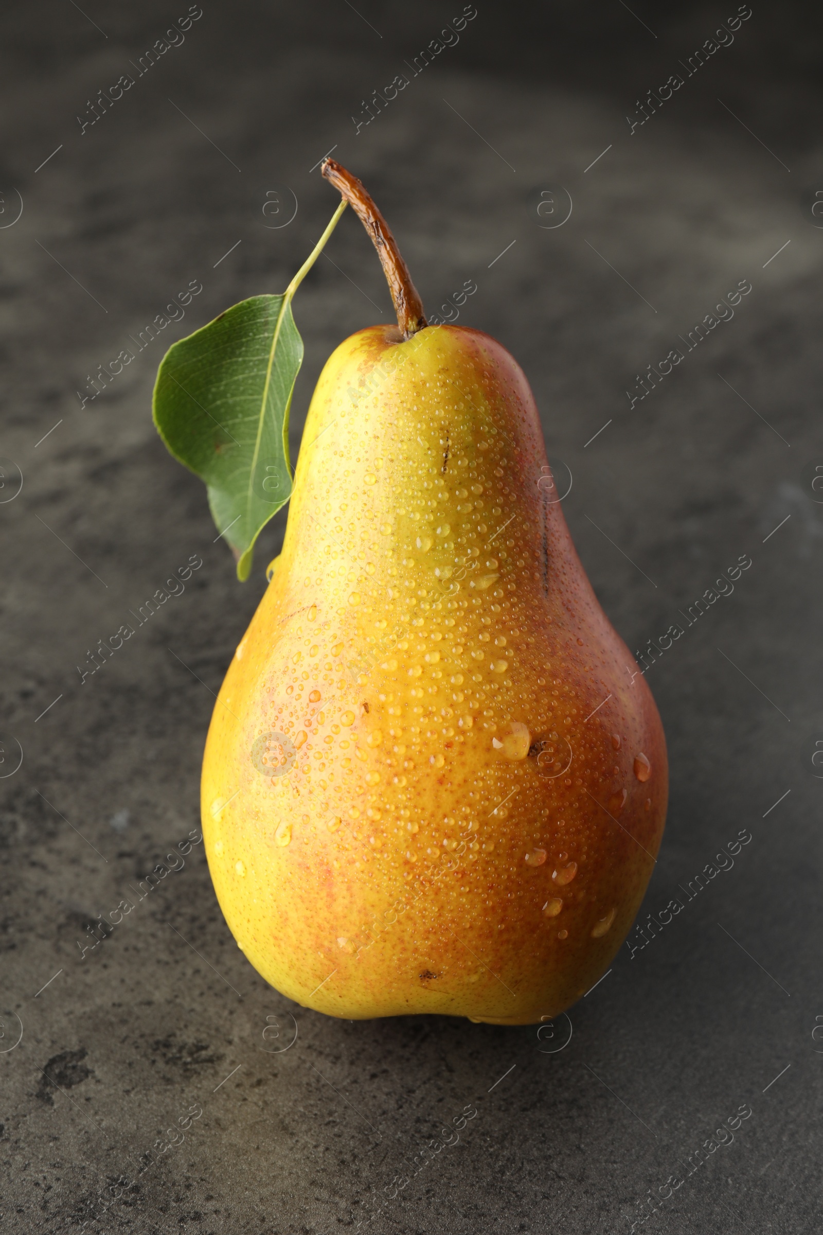 Photo of One ripe juicy pear on grey table, closeup