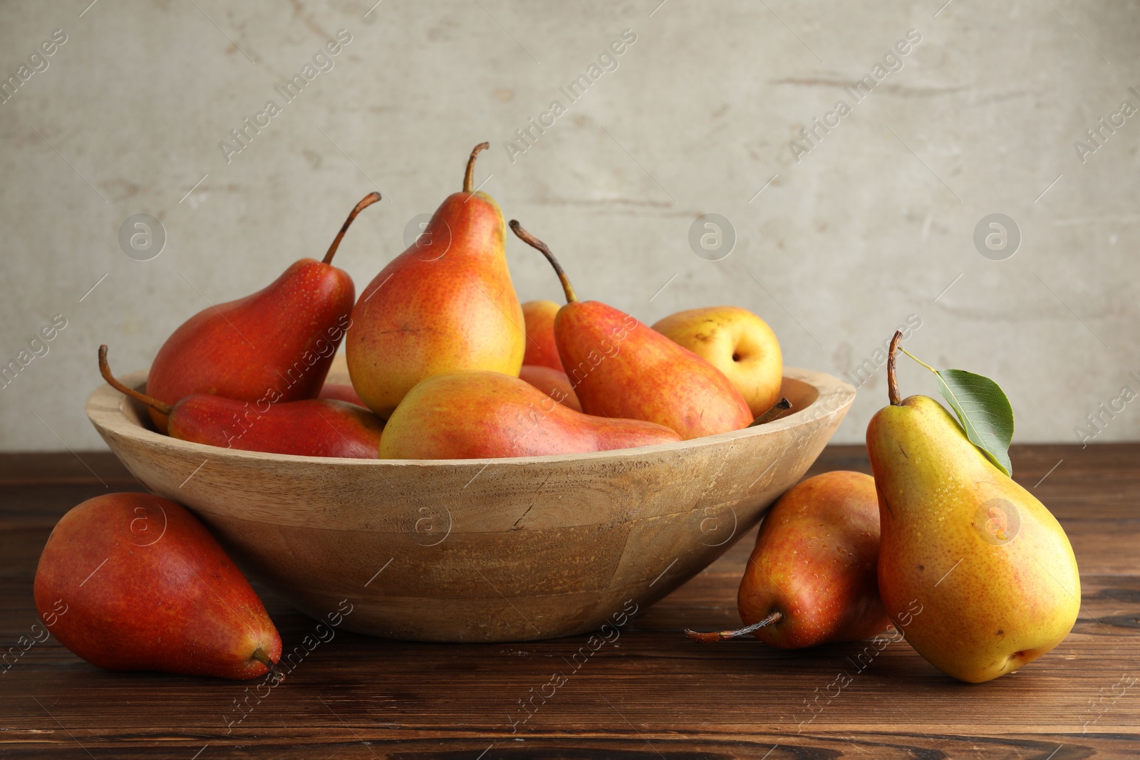 Photo of Ripe juicy pears in bowl on wooden table