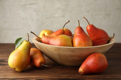 Photo of Ripe juicy pears in bowl on wooden table