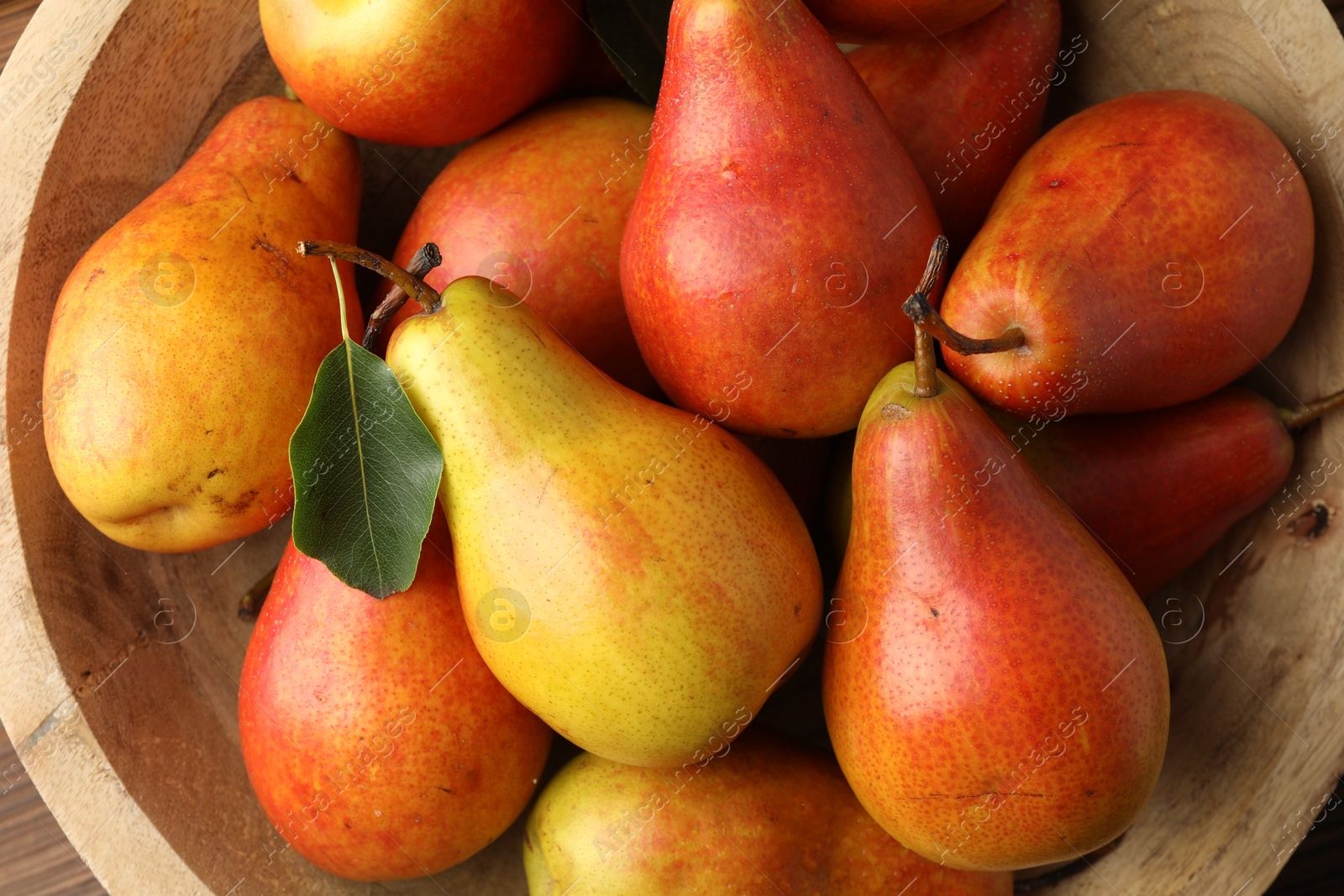 Photo of Ripe juicy pears in bowl, top view