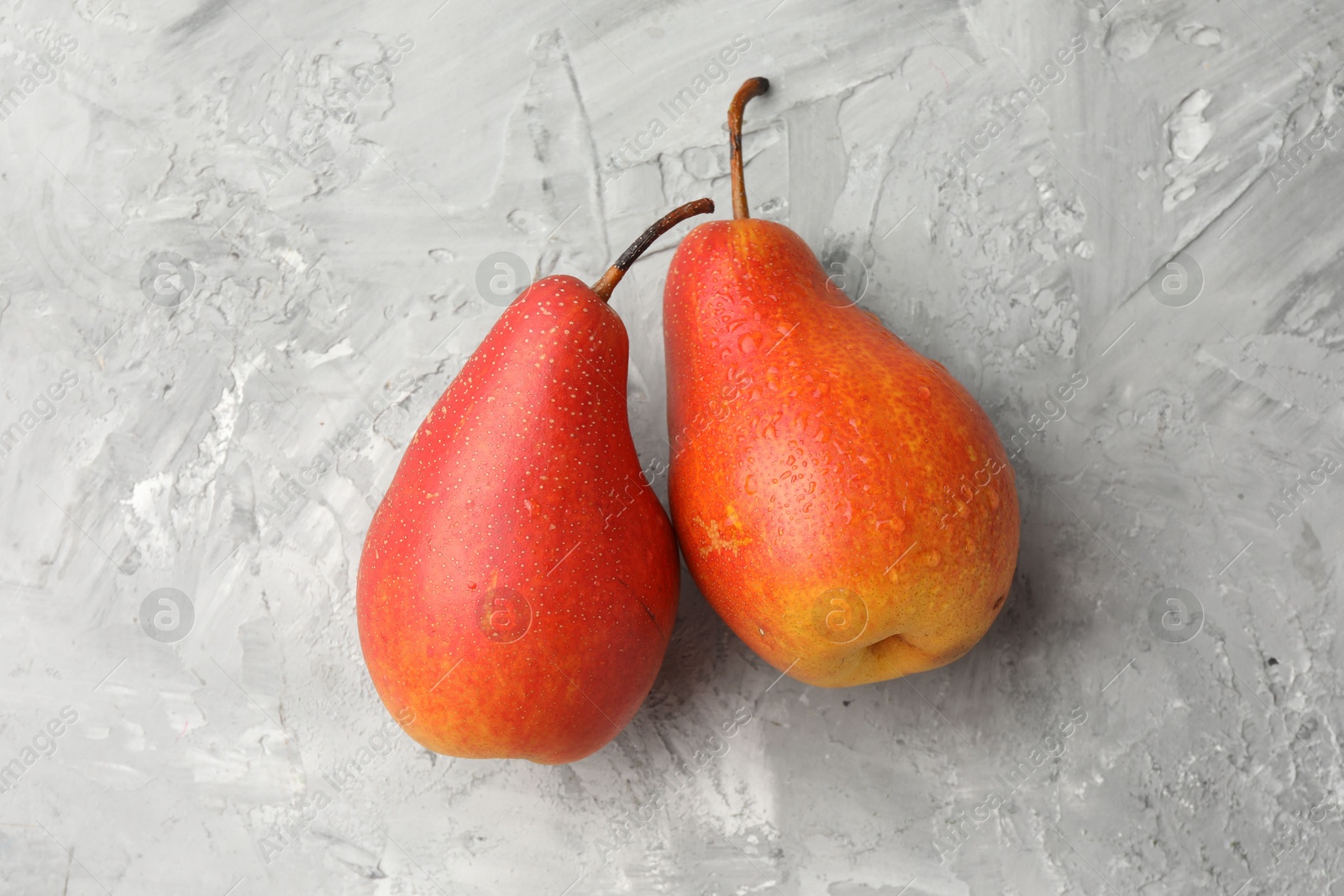 Photo of Two ripe juicy pears on grey table, top view