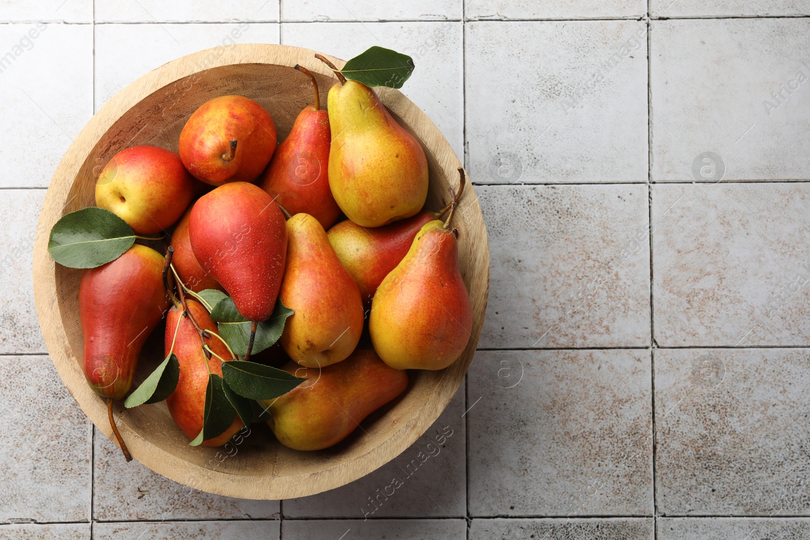 Photo of Ripe juicy pears on light tiled table, top view. Space for text