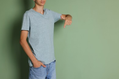 Photo of Teenage boy wearing light grey t-shirt on green background, closeup. Space for text