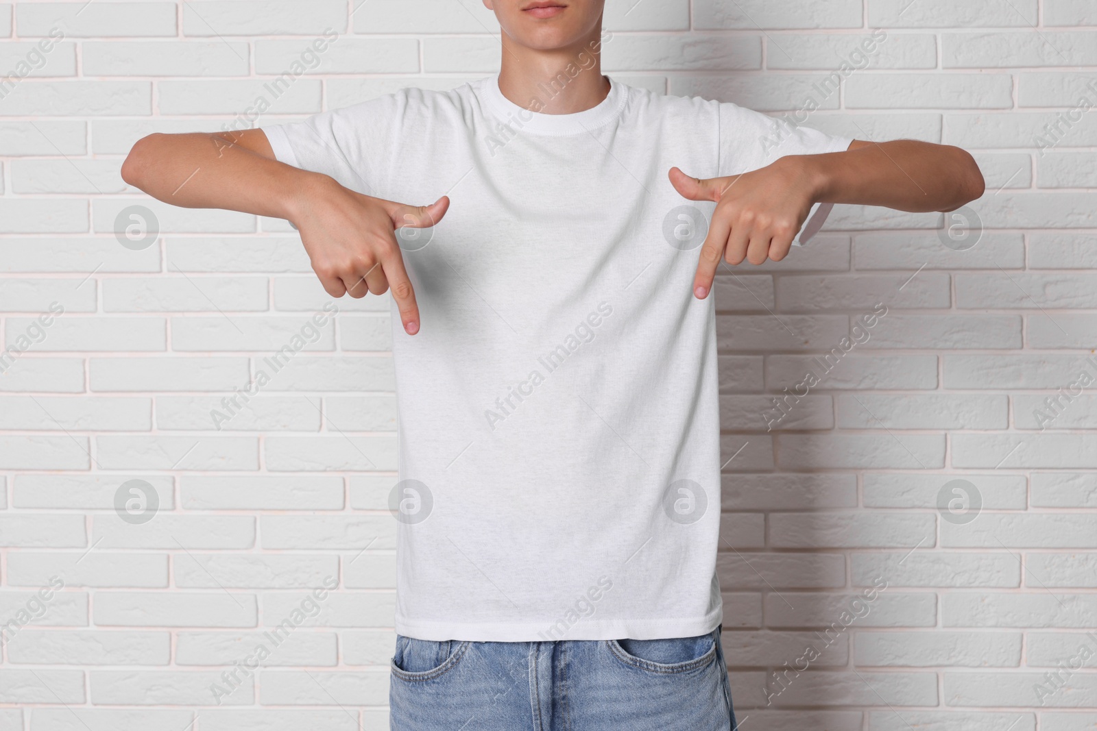 Photo of Teenage boy wearing t-shirt near white brick wall, closeup