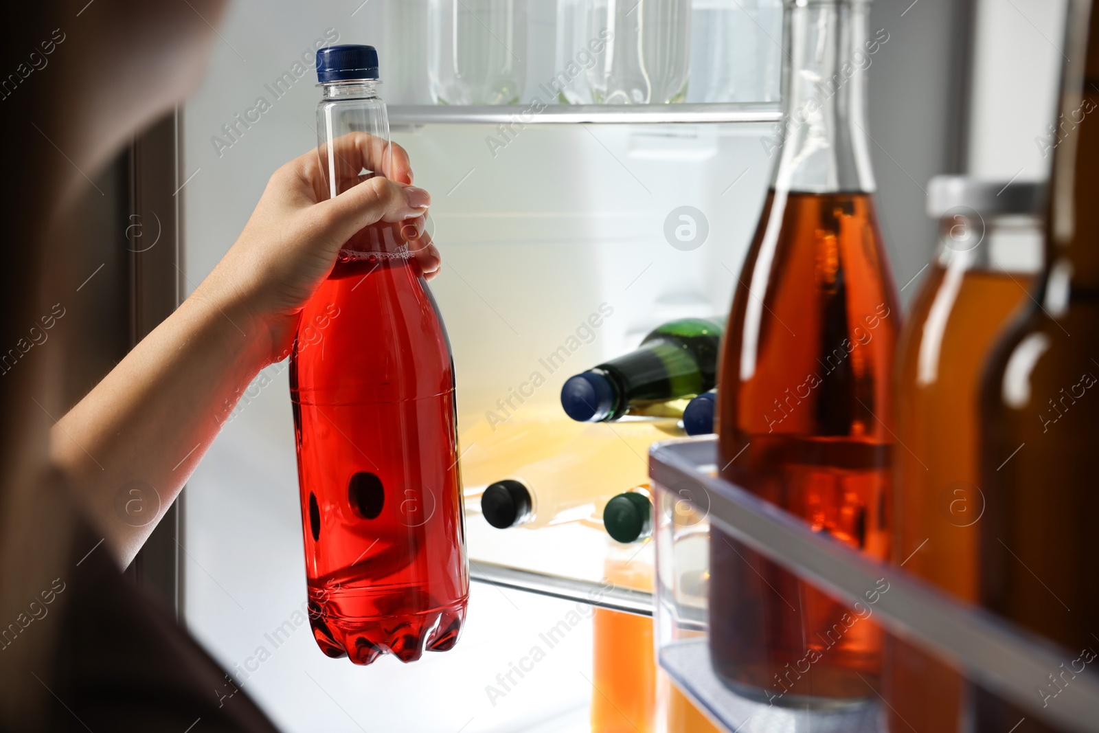 Photo of Woman taking bottle with drink from refrigerator, closeup