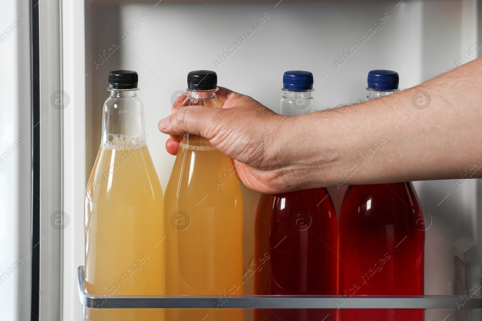 Photo of Woman taking bottle with drink from refrigerator, closeup