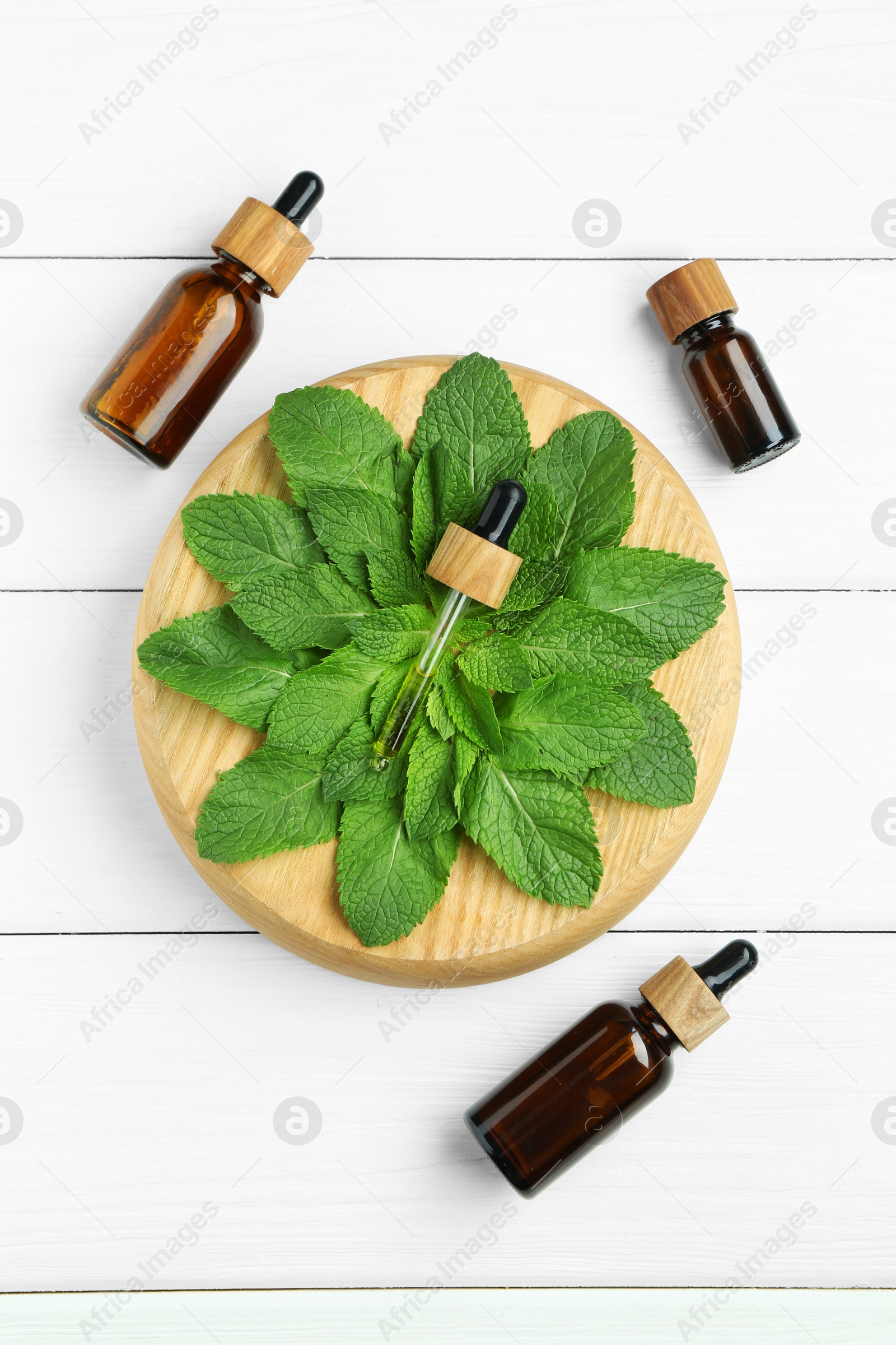 Photo of Tinctures in bottles, pipette and mint on white wooden table, top view