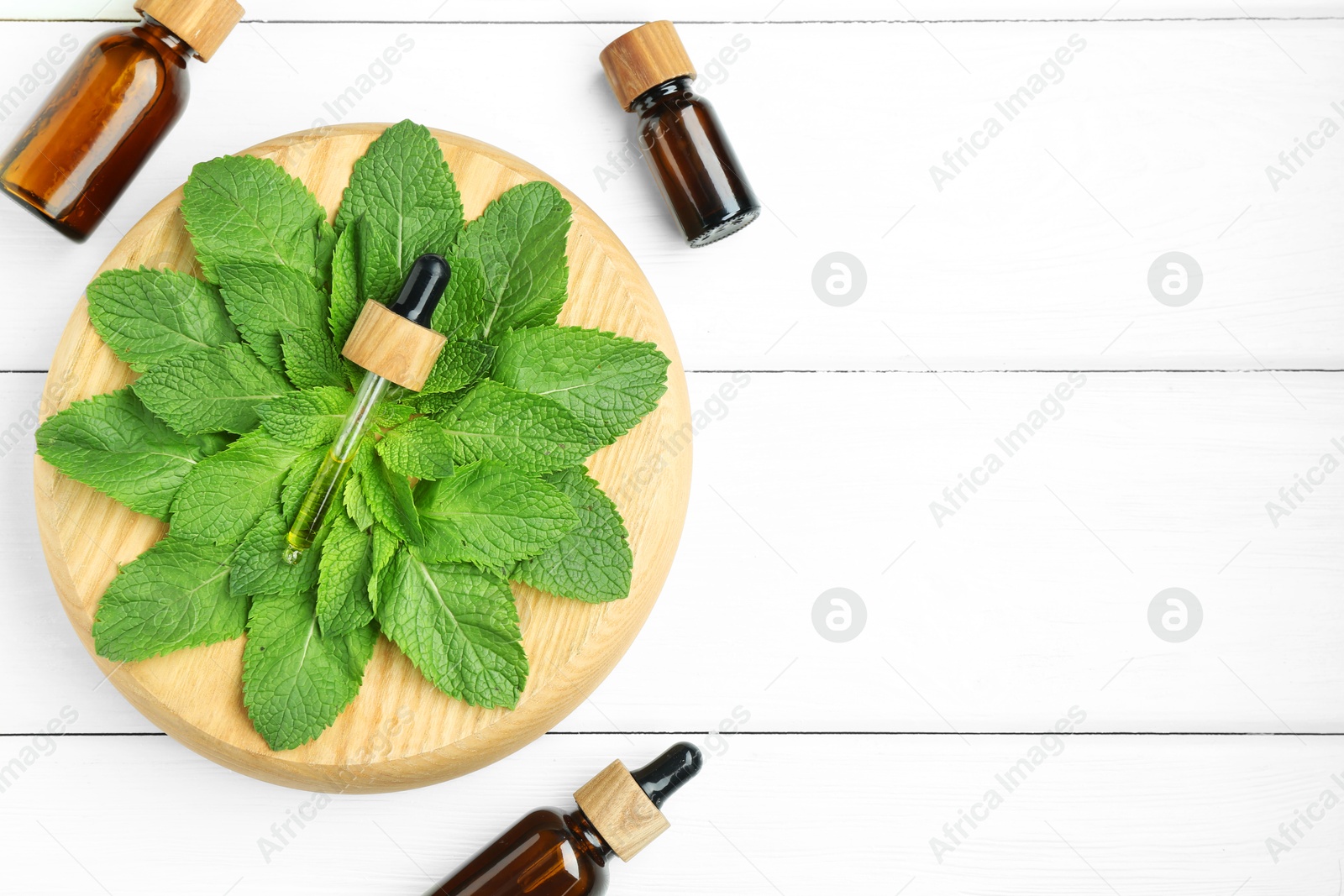 Photo of Tinctures in bottles, pipette and mint on white wooden table, top view. Space for text