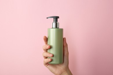 Photo of Woman with shampoo bottle on pink background, closeup