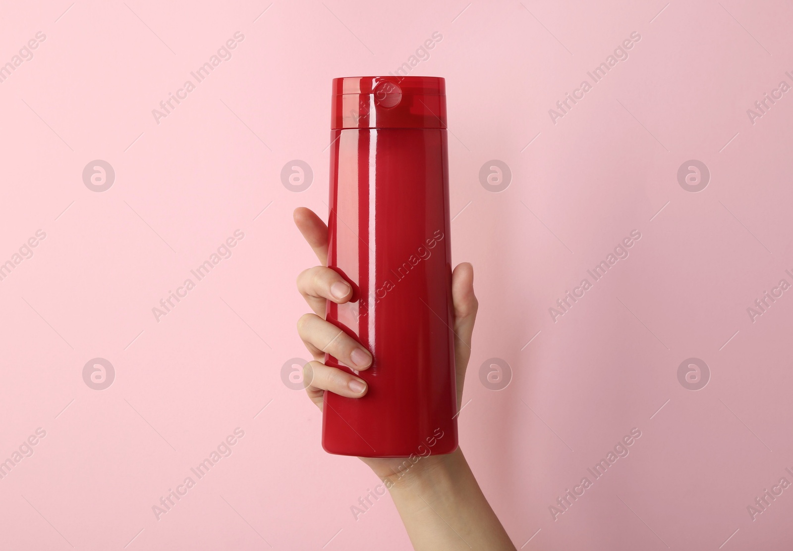 Photo of Woman with shampoo bottle on pink background, closeup