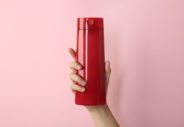 Photo of Woman with shampoo bottle on pink background, closeup