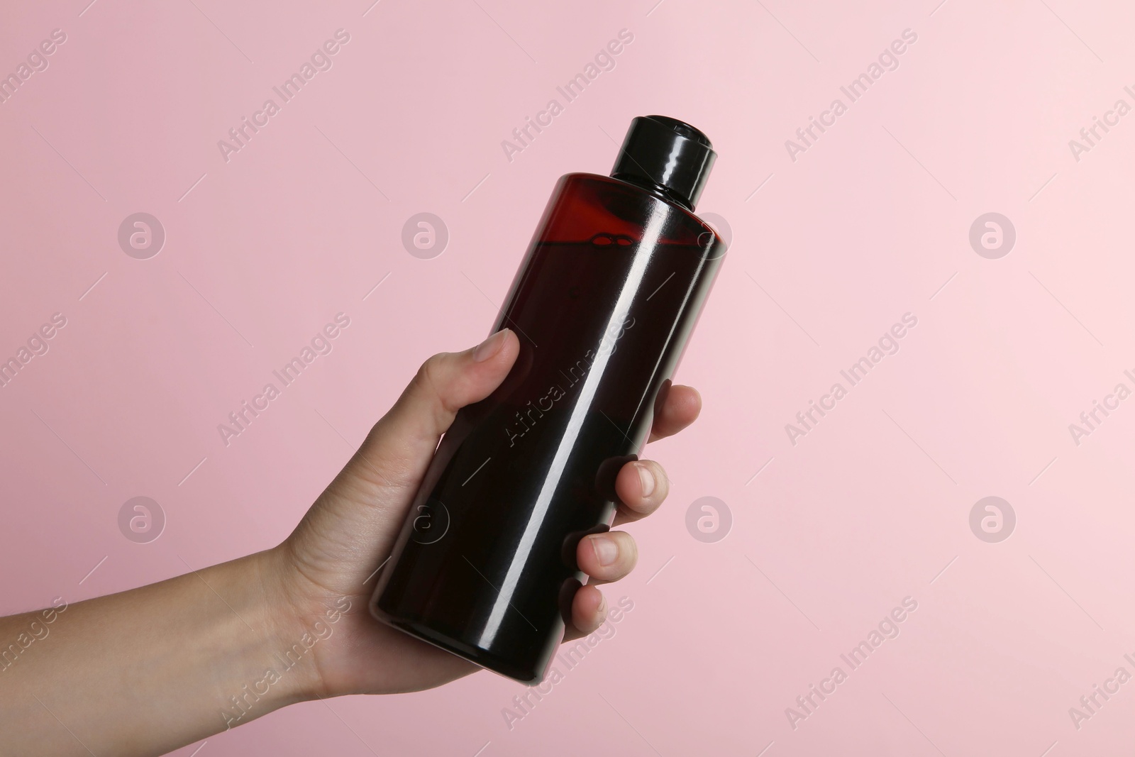 Photo of Woman with shampoo bottle on pink background, closeup