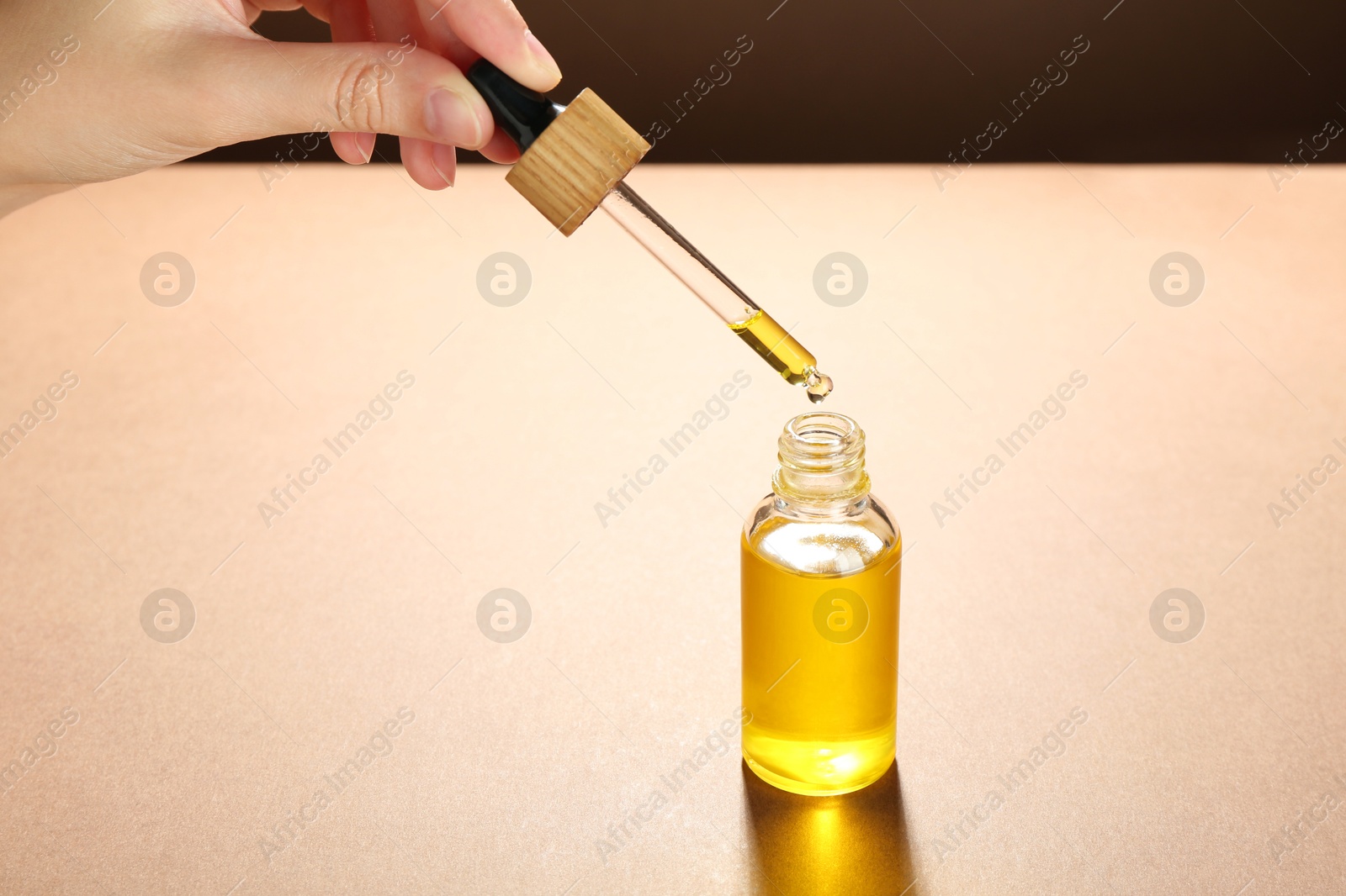 Photo of Woman dripping tincture from pipette into bottle on color background, closeup