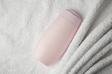 Photo of Bottle of shampoo on soft terry towel, top view