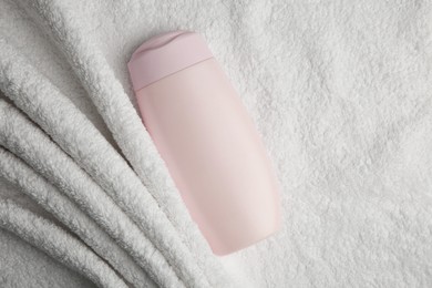 Photo of Bottle of shampoo on soft terry towel, top view