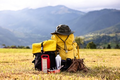 Backpack, trekking shoes and other camping equipment on grass outdoors