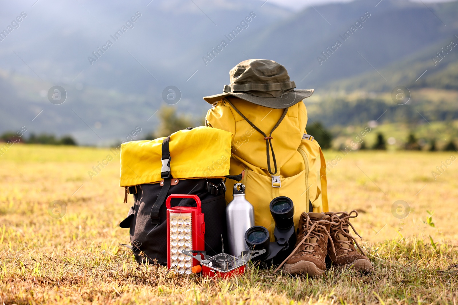 Photo of Backpack, trekking shoes and other camping equipment on grass outdoors