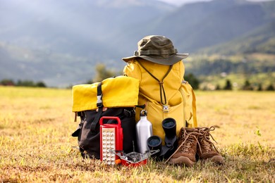 Backpack, trekking shoes and other camping equipment on grass outdoors