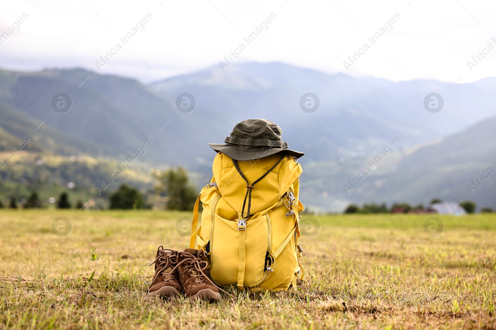 Photo of Backpack, hat and trekking shoes on grass outdoors