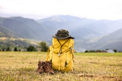 Photo of Backpack, hat and trekking shoes on grass outdoors