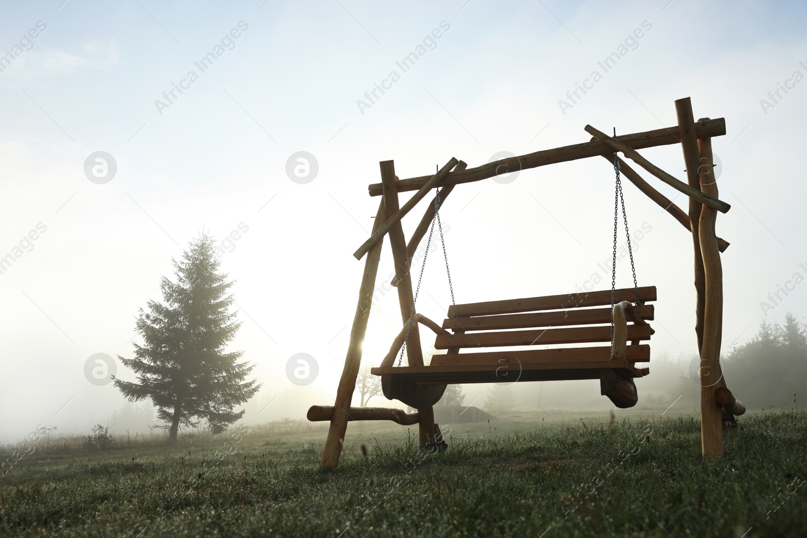 Photo of Wooden swing outdoors in morning, low angle view