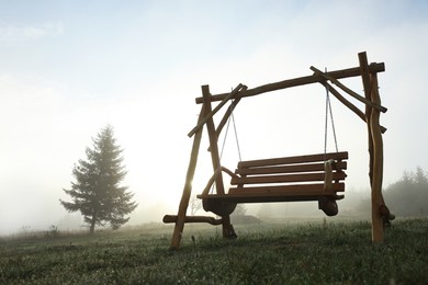 Photo of Wooden swing outdoors in morning, low angle view