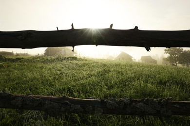 Photo of Cobweb with morning dew drops on wooden fence outdoors