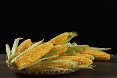 Photo of Many fresh ripe corncobs with green husks on wooden table. Space for text