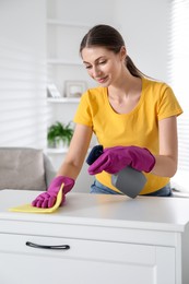 Young woman cleaning table with rag and spray in office