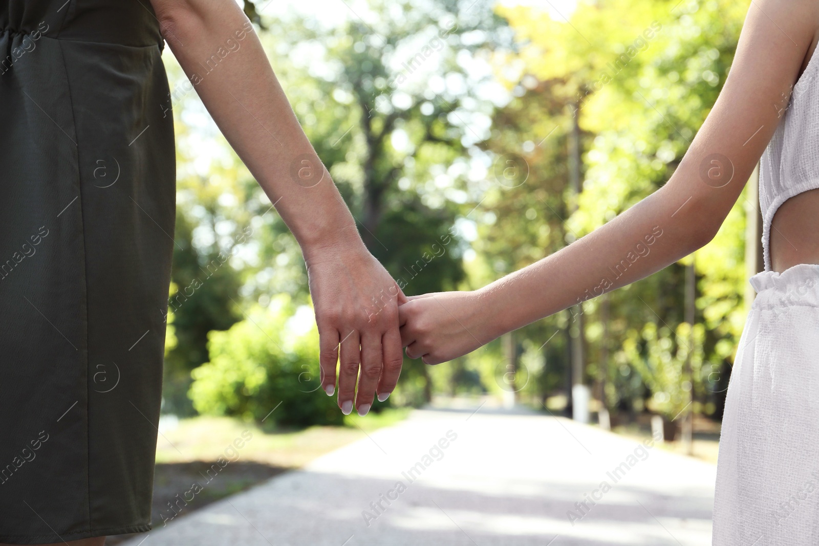 Photo of Mother and daughter holding hands in park, closeup