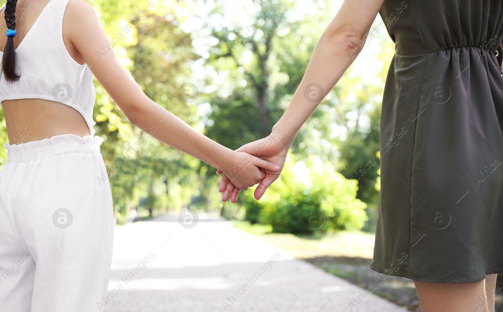 Photo of Mother and daughter holding hands in park, closeup