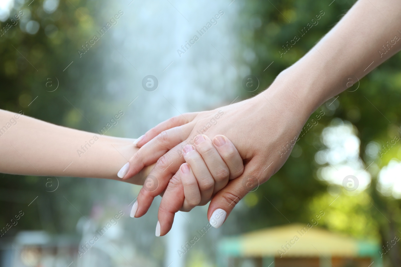 Photo of Mother and daughter holding hands in park, closeup