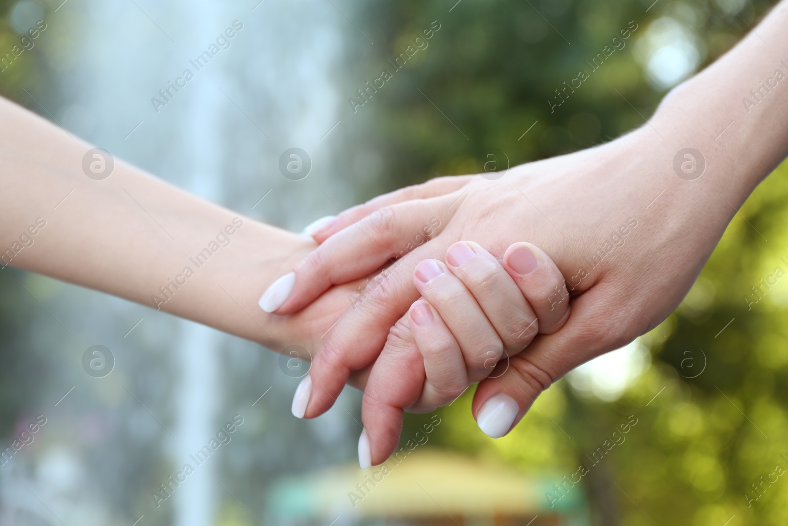 Photo of Mother and daughter holding hands in park, closeup