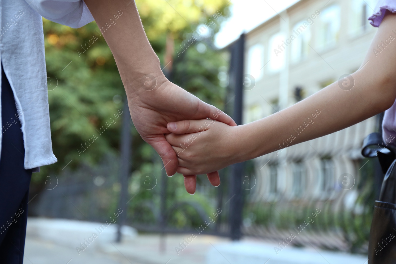 Photo of Mother and daughter holding hands outdoors, closeup