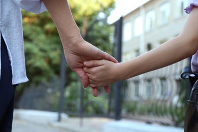 Photo of Mother and daughter holding hands outdoors, closeup