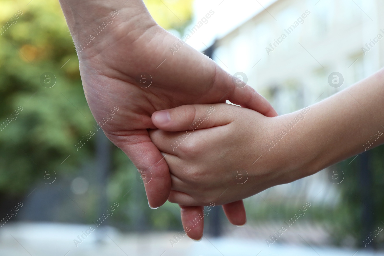 Photo of Mother and daughter holding hands outdoors, closeup