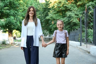 Photo of Happy mother and daughter holding hands outdoors