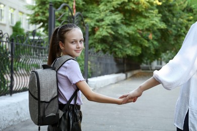 Mother and daughter holding hands outdoors, closeup