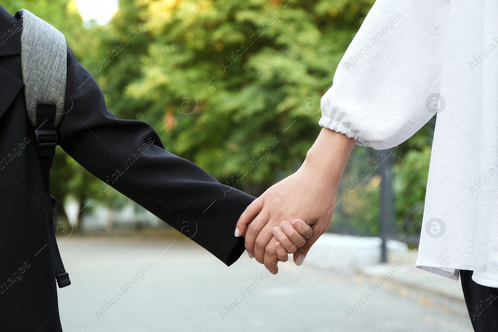 Photo of Mother and daughter holding hands outdoors, closeup