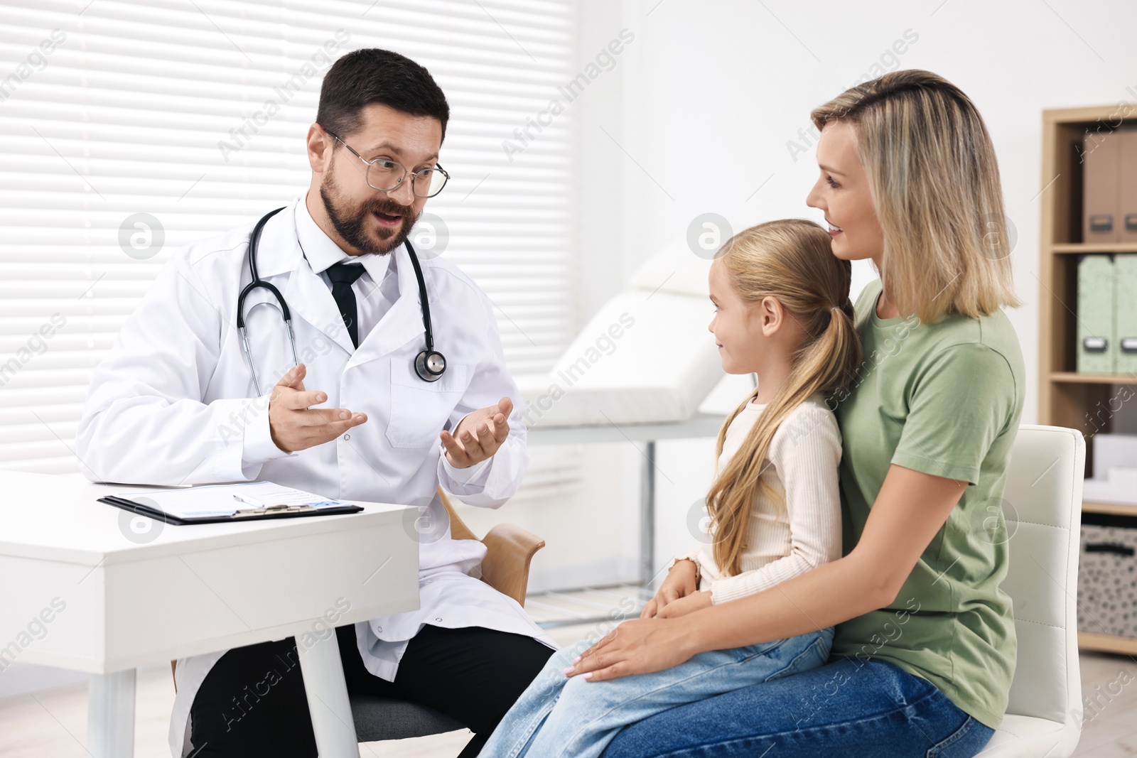 Photo of Doctor consulting little girl and her mother in hospital