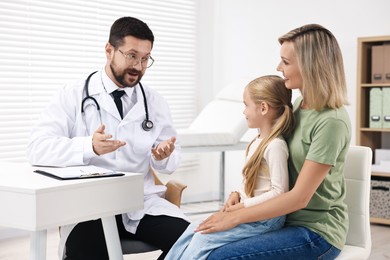 Doctor consulting little girl and her mother in hospital