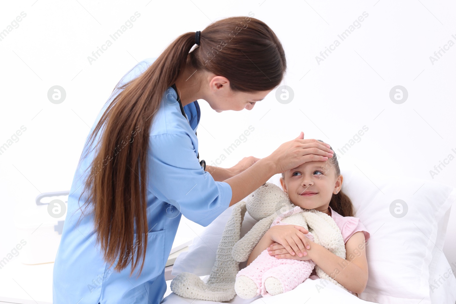 Photo of Doctor examining little girl on bed at hospital