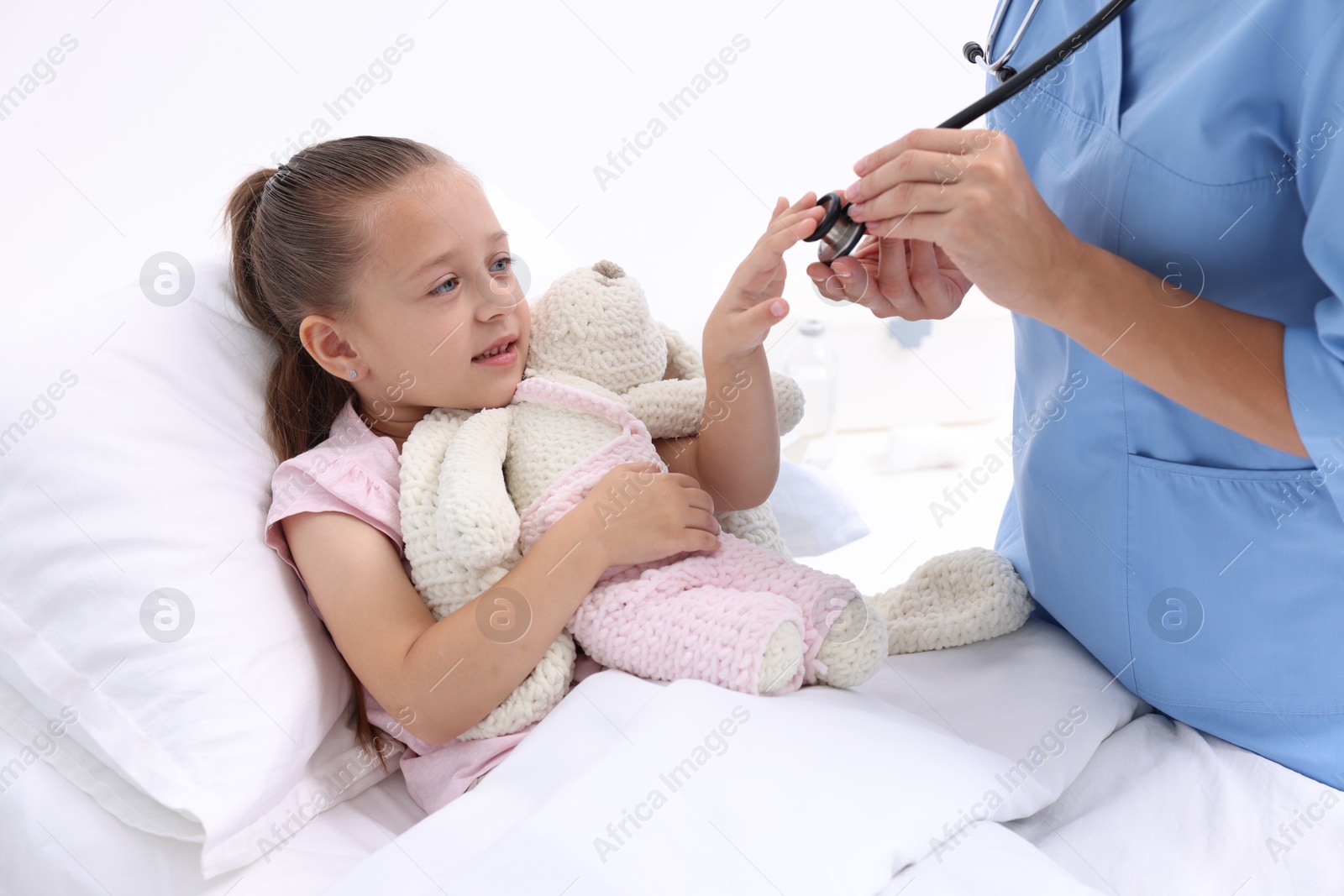 Photo of Doctor examining little girl on bed at hospital, closeup