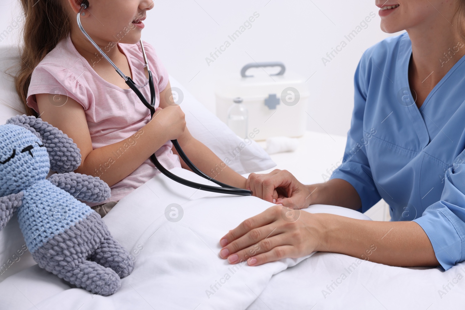 Photo of Doctor examining little girl on bed at hospital, closeup