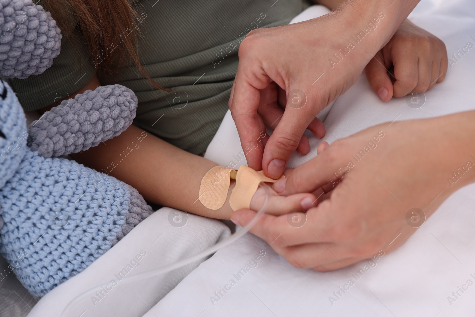 Photo of Doctor examining little girl on bed at hospital, closeup