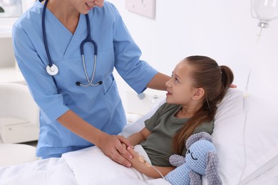 Doctor examining little girl on bed at hospital, closeup