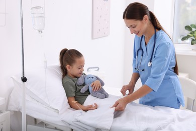 Doctor examining little girl on bed at hospital